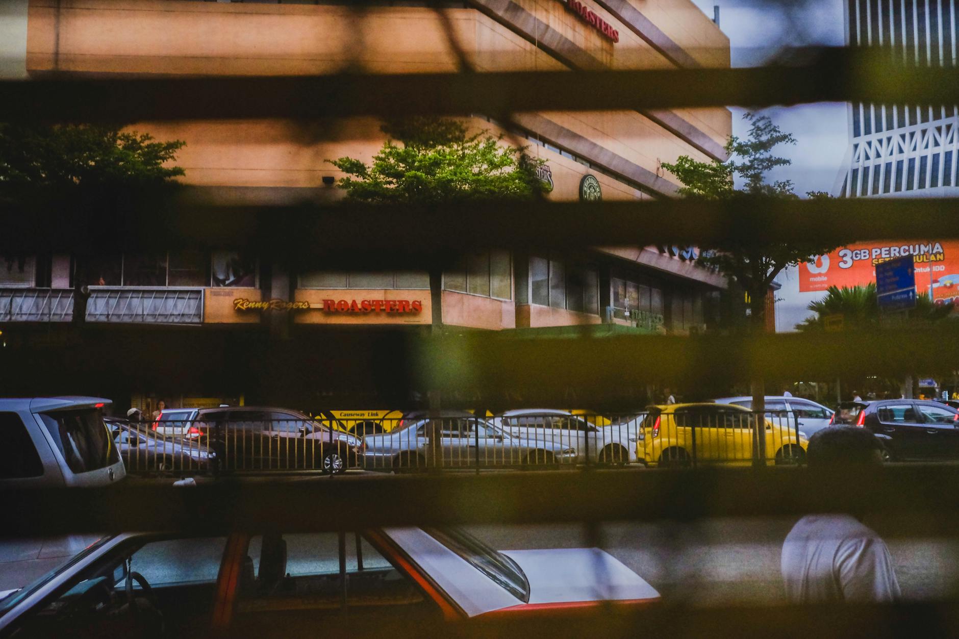 cars stuck in traffic seen trough window blinds