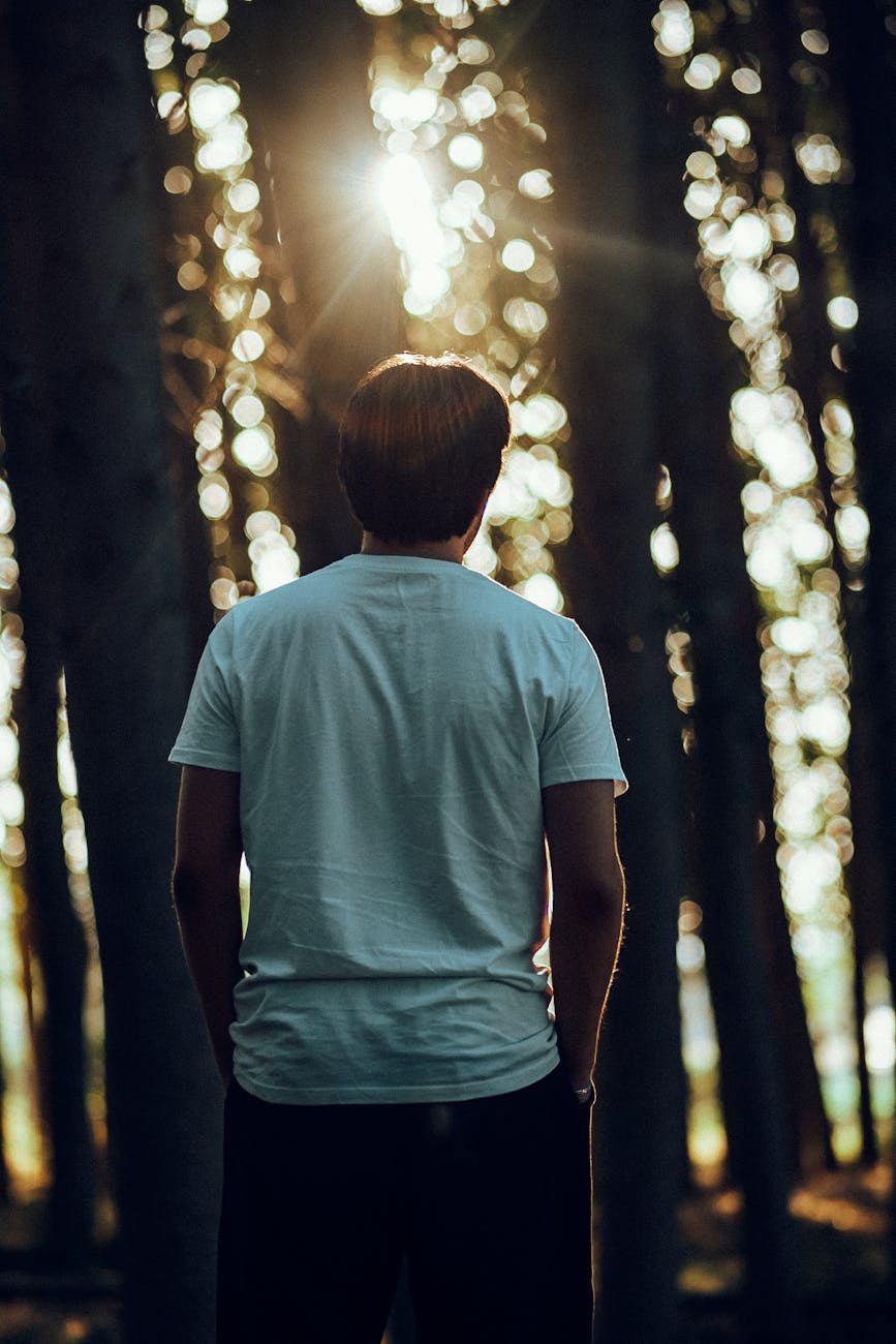 man in forest with sunlight streaming through trees