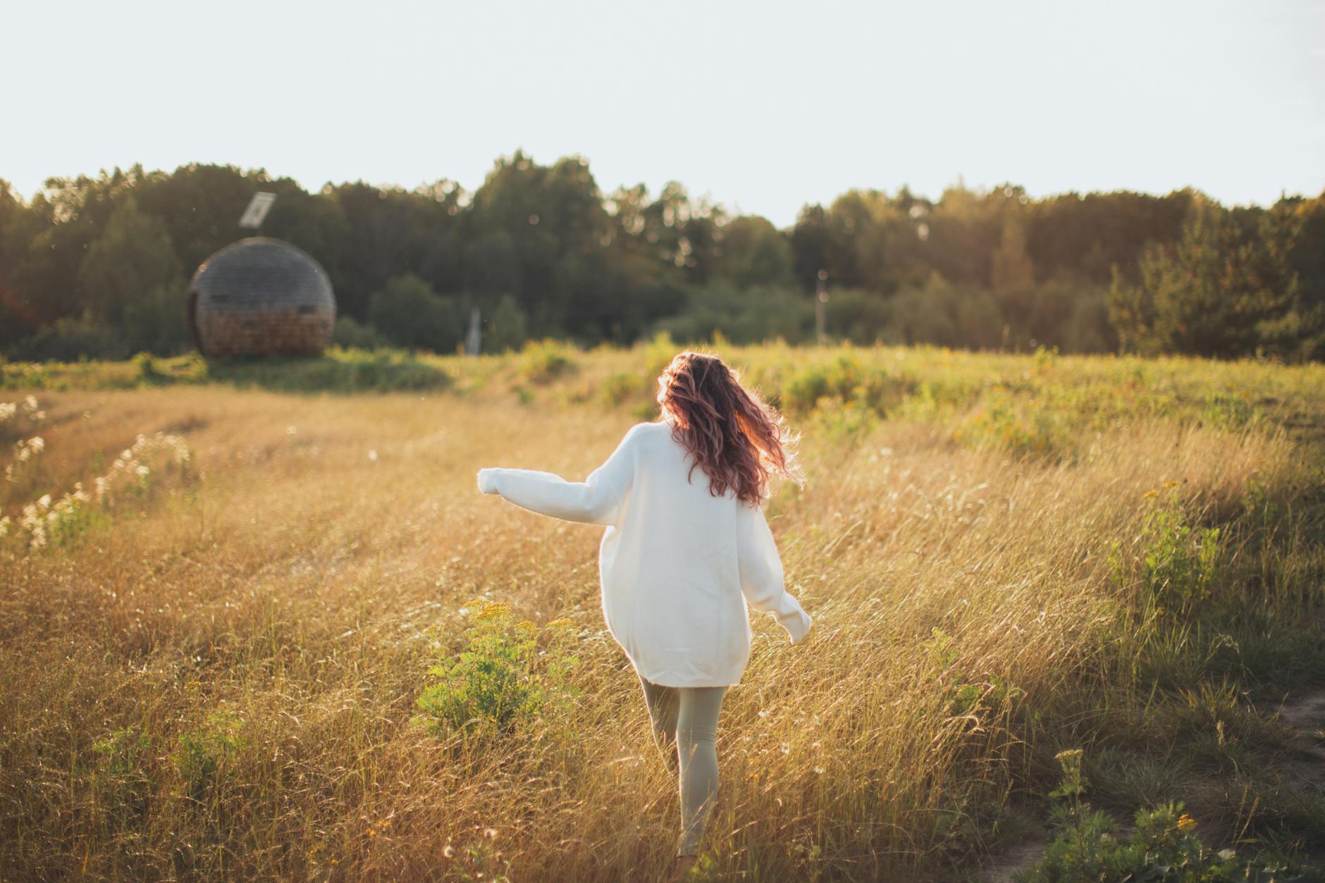 woman wearing white jacket while walking on grass field